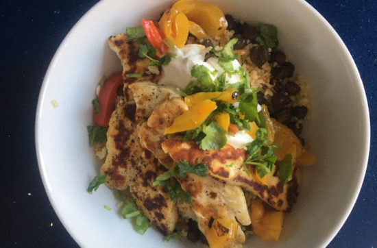 Bowl of black chick pea, cous cous, carrot and coriander warm salad with halloumi and yoghurt